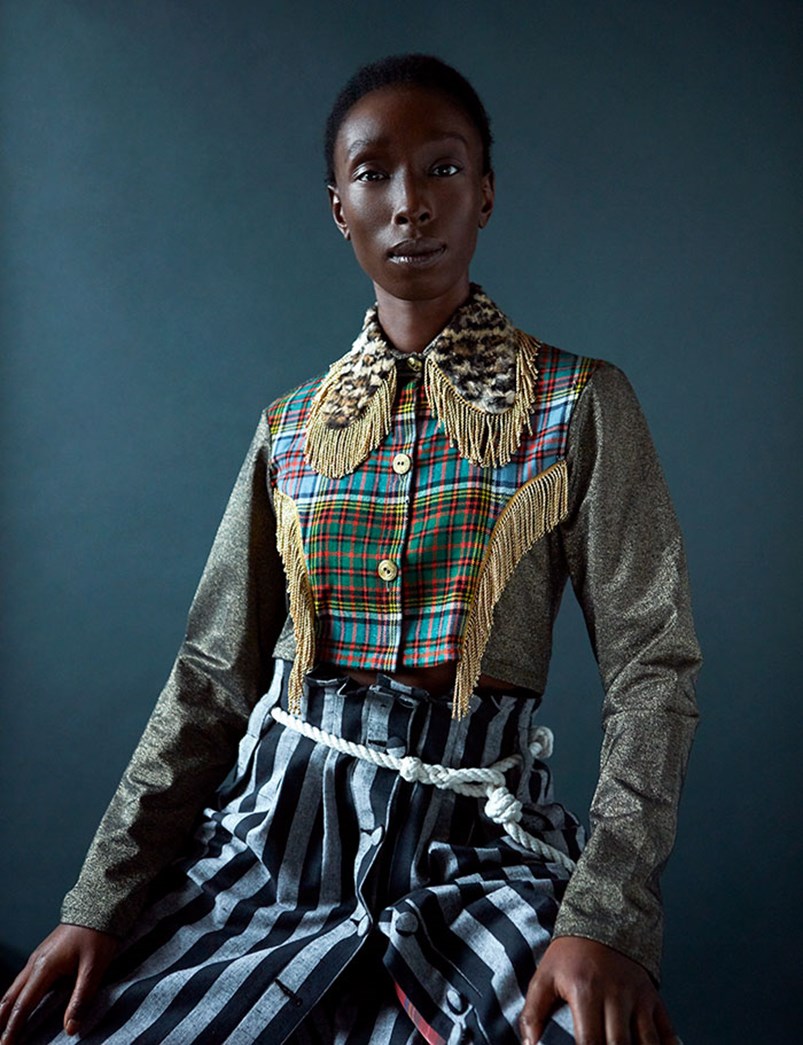 Eunice Olumide sitting wearing a tartan top and striped trousers.