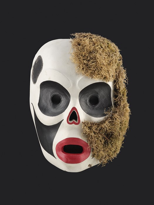 Black, white and red mask with moss on half the face.