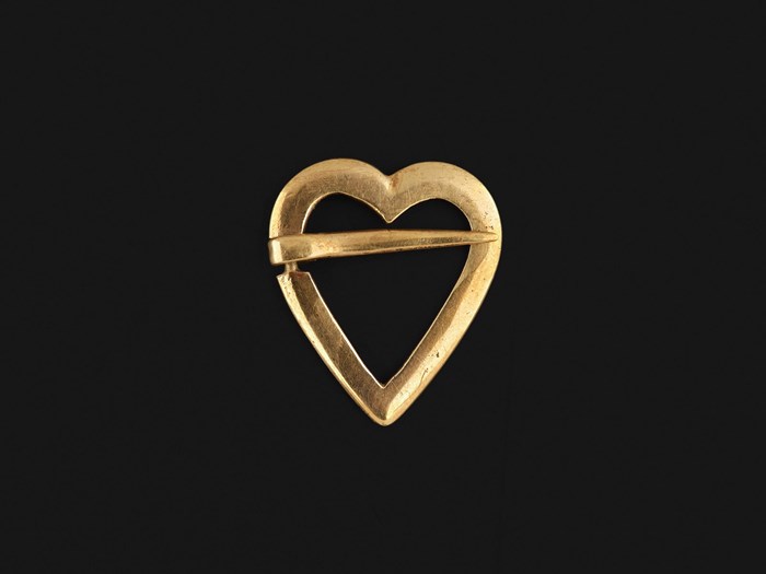 A simple heart-shaped brooch designed like the classic drawn heart. A short pin crosses the top third of the brooch.