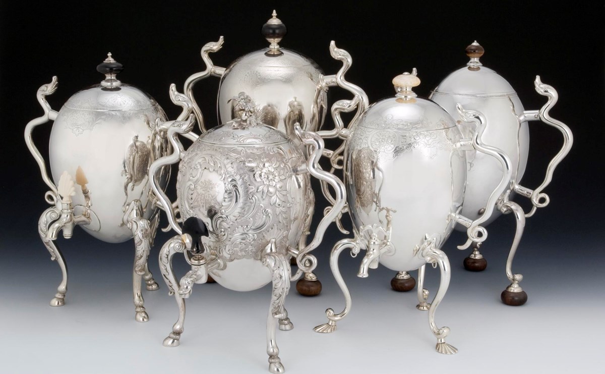 Five large silver coffee pots shaped like eggs propped up on tall, curving legs and with spindly arms, some of them made to resemble serpents. They look a bit sci-fi, and are very shiny.