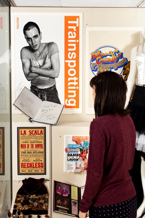 A visitor looks at a display case with items about entertainment in Scotland.