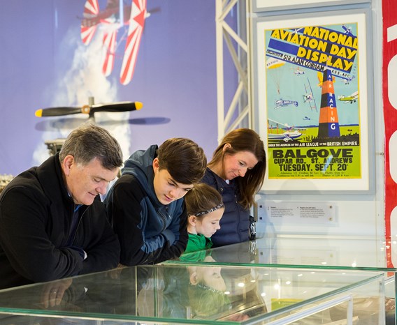 Four visitors look into lit glass case.