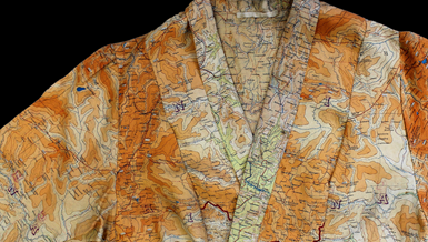 The neck of a dress made from silk 'escape and evade' maps in bright oranges.