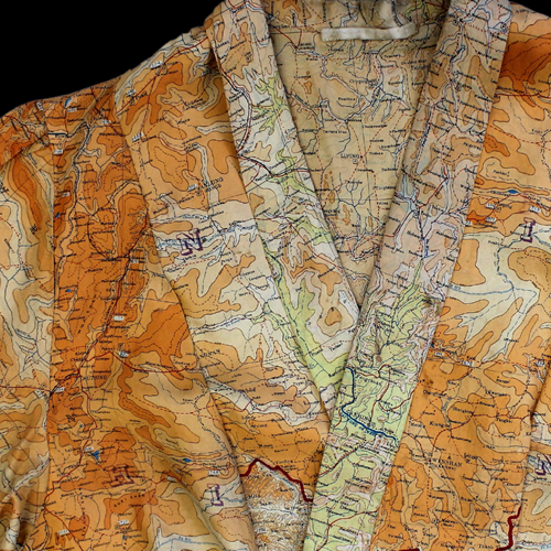 The neck of a dress made from silk 'escape and evade' maps in bright oranges.