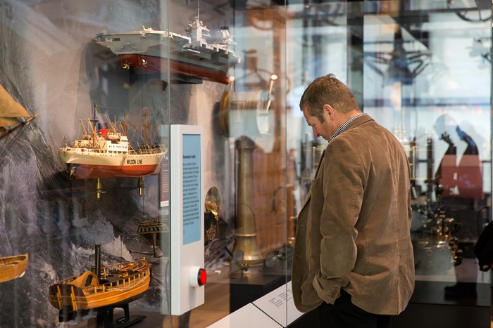 Man looking at a model ship in a glass cabinet at National Museum of Scotland.