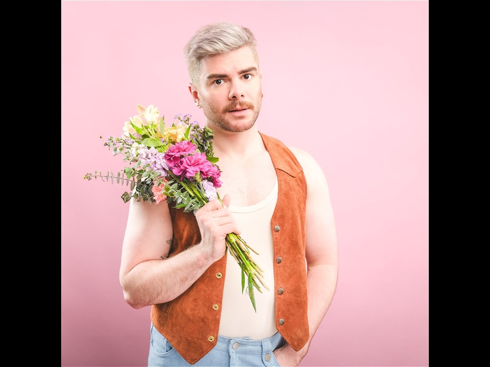 Christopher Hall standing holding a bunch of flowers 