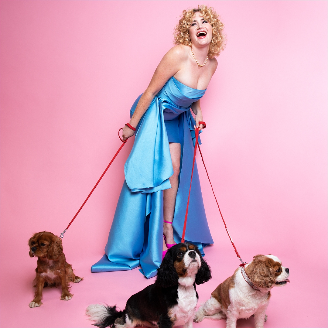 Grace Gampbell wearing a light blue gown and holding onto the leads of three spaniels