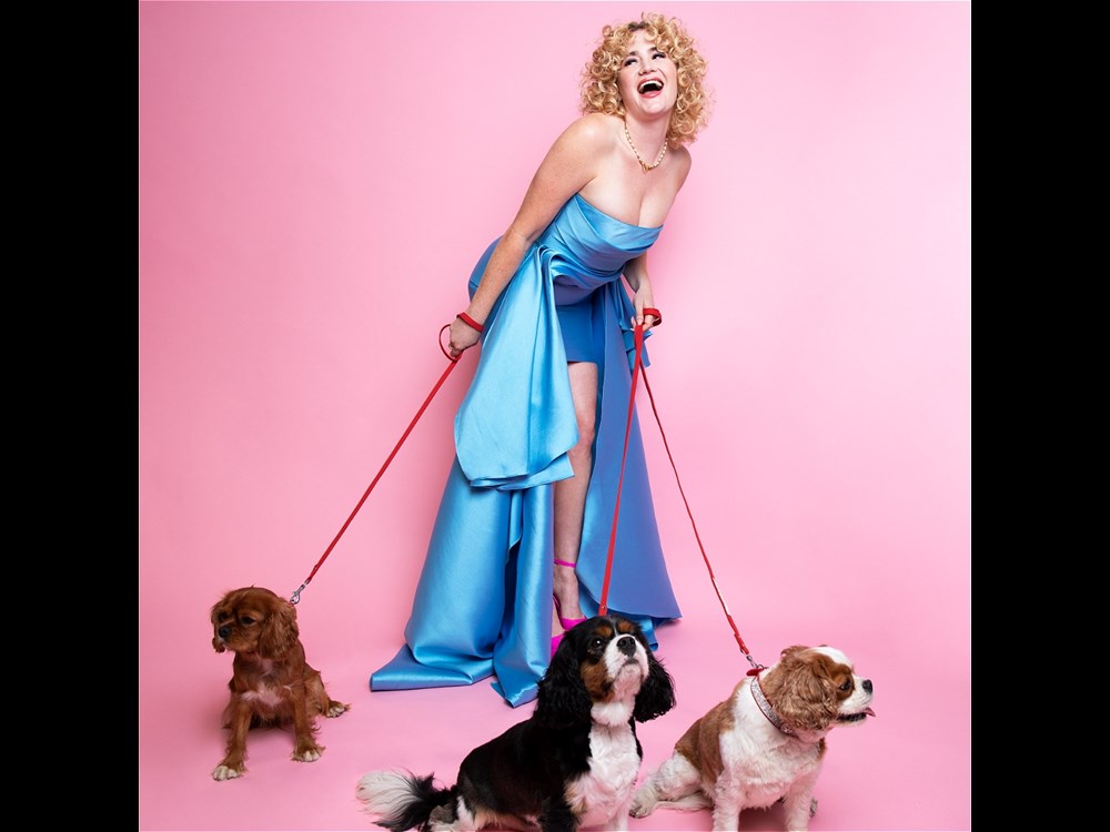 Grace Gampbell wearing a light blue gown and holding onto the leads of three spaniels